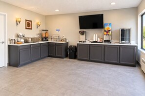 A modern kitchen with grey cabinets, a flat-screen TV, and a coffee station. - Crestview Inn Branson West by Silver Dollar City (Branson West)