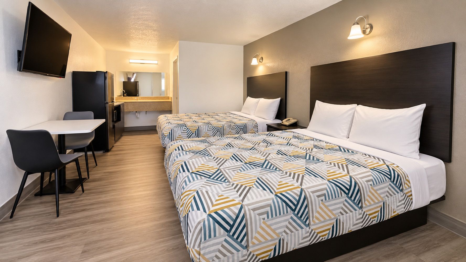 A hotel room with two beds, a desk, and a chair.