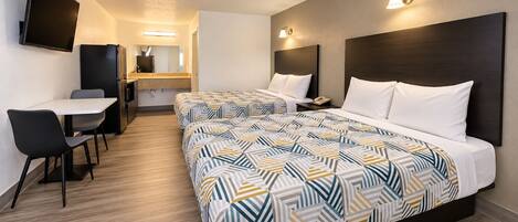 A hotel room with two beds, a desk, and a chair.