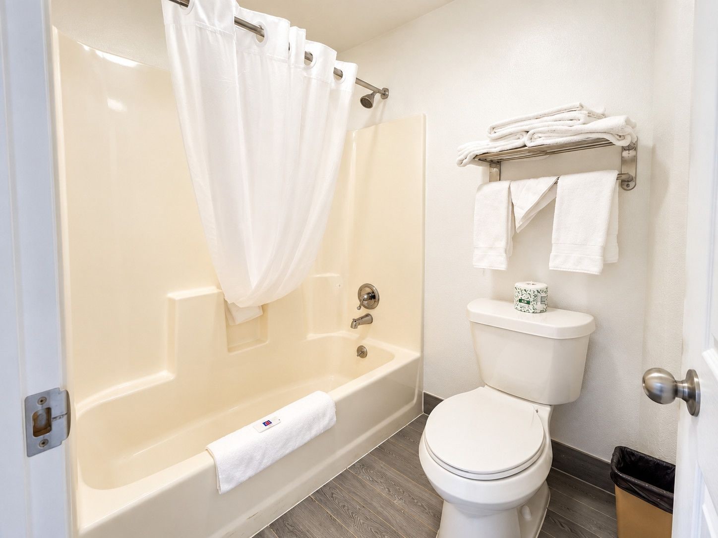 A bathroom with a bathtub, toilet, and a towel rack with towels.