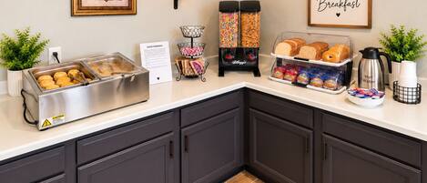 A breakfast bar with various food items and a coffee machine.