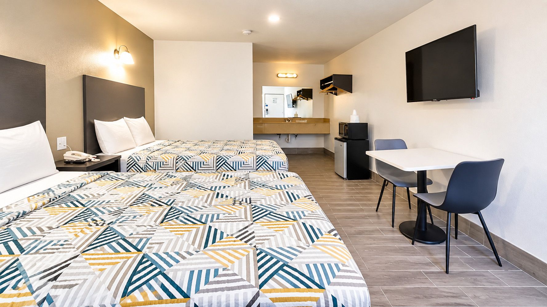 Une chambre d’hôtel avec un grand lit, un bureau, une chaise, une télévision et une salle de bain que l’on aperçoit à l’arrière-plan.