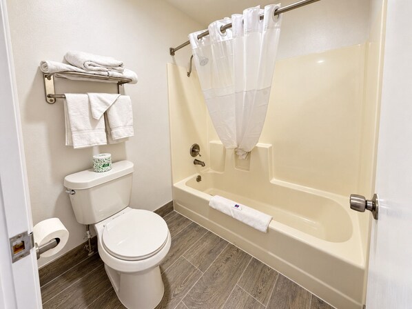 A bathroom with a toilet, a sink, and a bathtub with a shower curtain. - Crestview Inn Branson West by Silver Dollar City (Branson West)