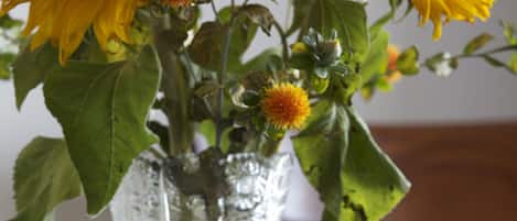 A clear glass vase with a floral arrangement including sunflowers and other flowers.