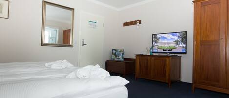Una habitación de hotel con cama, cómoda, televisor y armario.