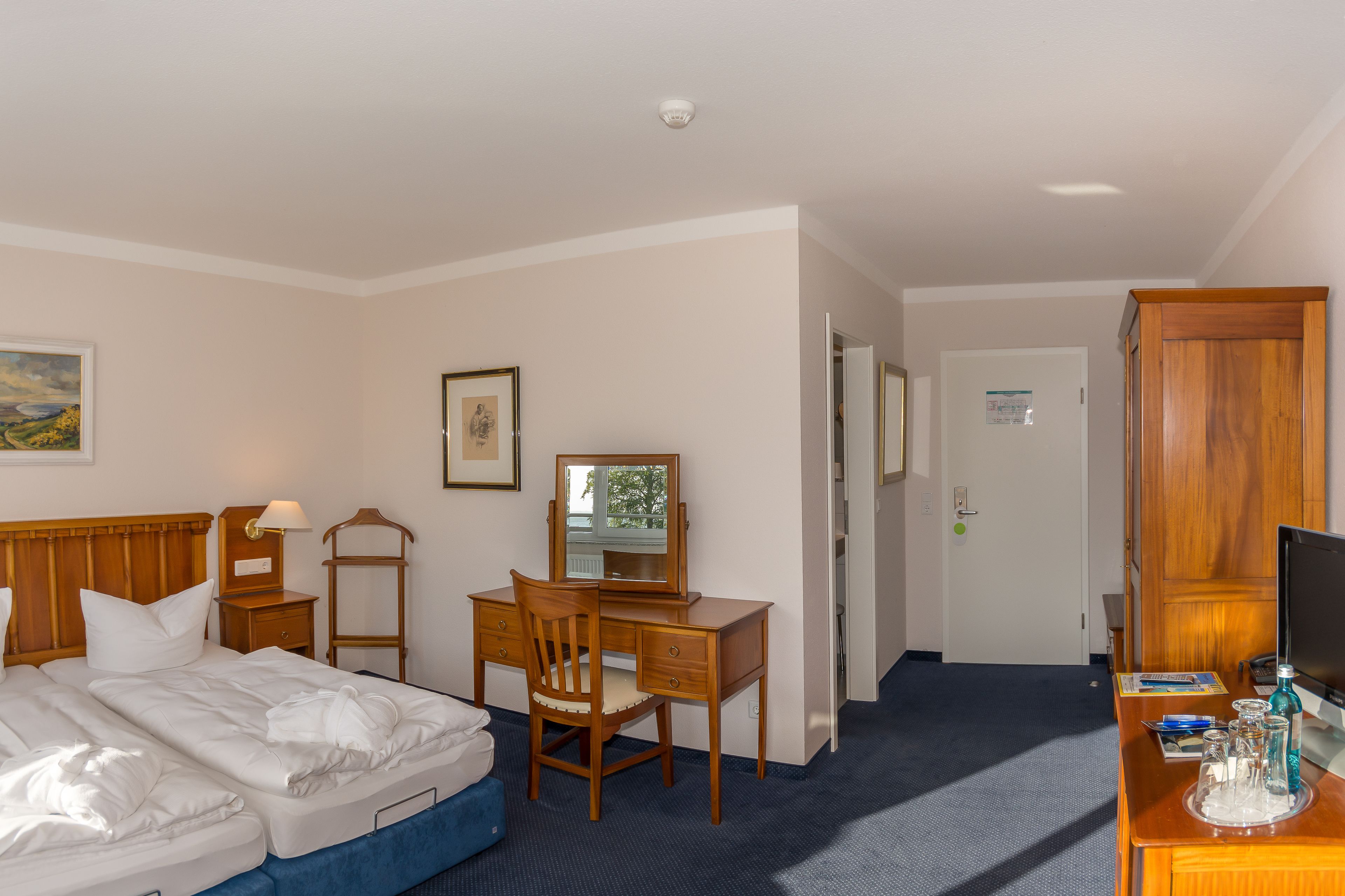 Habitación de hotel con cama, escritorio, silla y televisión.