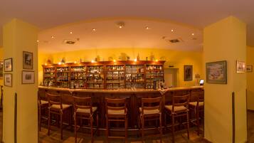 A bar area with wooden chairs and shelves stocked with bottles and glasses.
