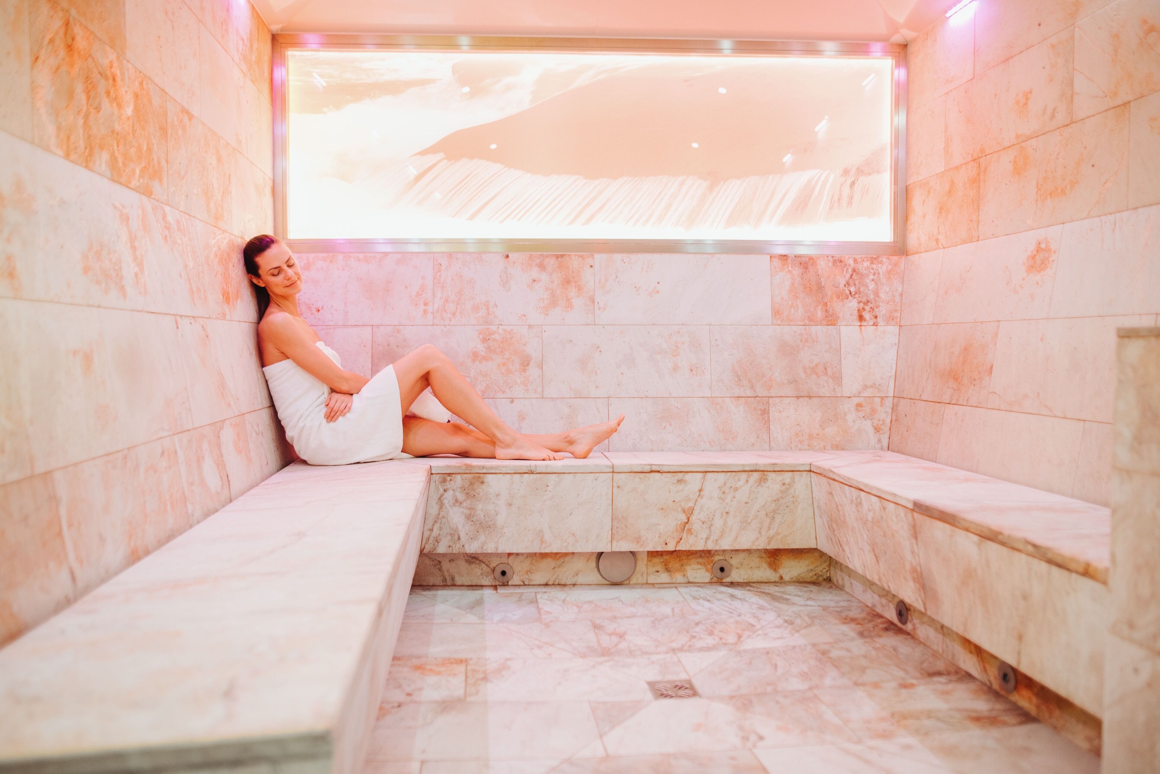 A spa room with a marble bench and a large window.