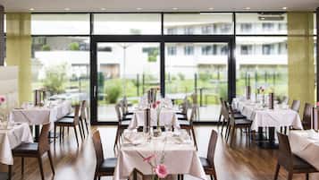 Un comedor con mesas dispuestas para el servicio, ventanas amplias con vistas al exterior y un diseño de interiores moderno.