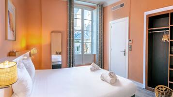 A hotel room with a bed, a bedside lamp, a wardrobe, and a window with curtains.