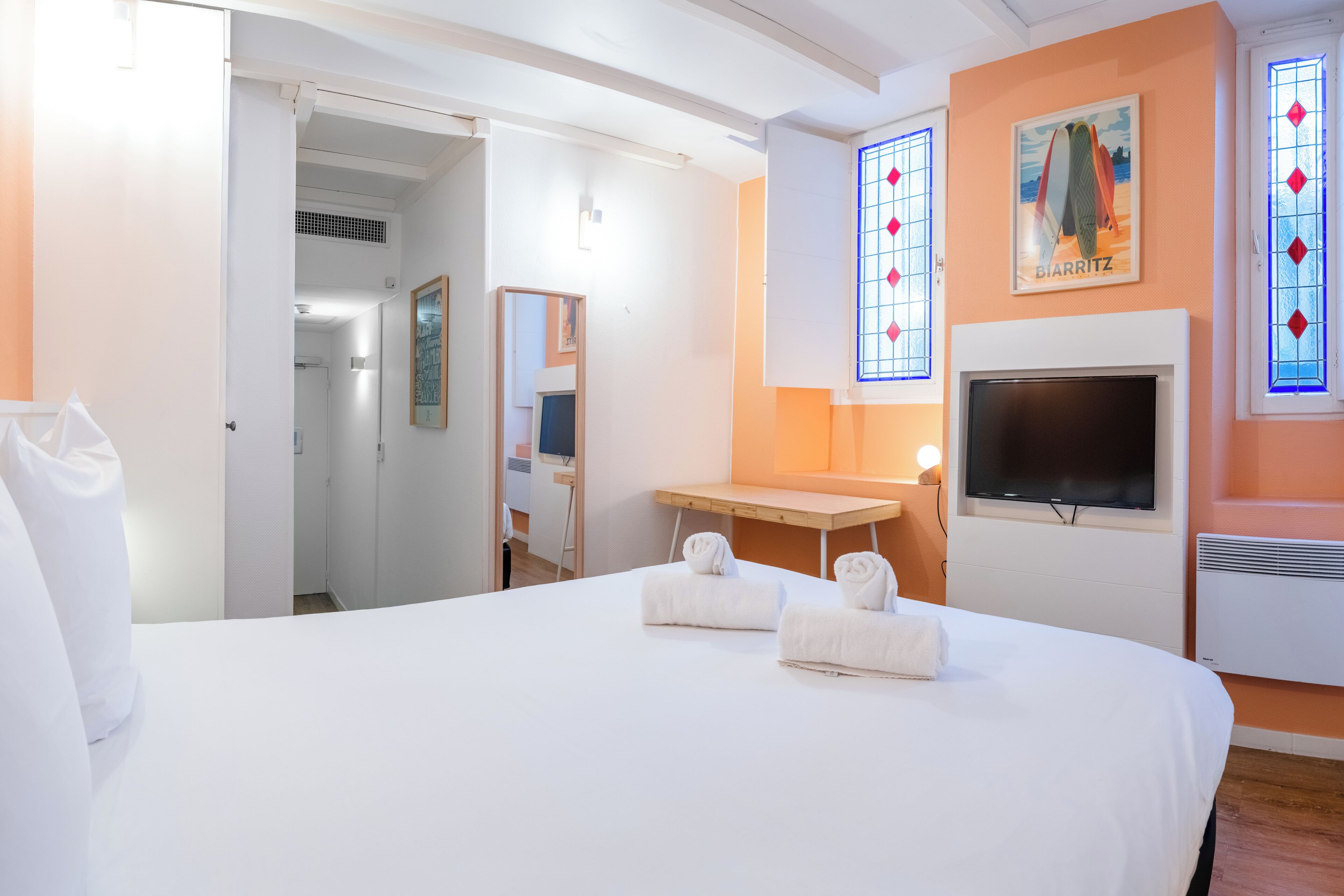 A hotel room with a bed, a TV, a fireplace, and a bathroom visible through an open door.
