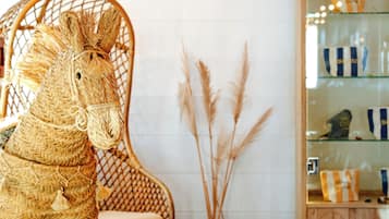 Una escultura de caballo de mimbre, una silla de mimbre y una vitrina de vidrio con bolsos a rayas.