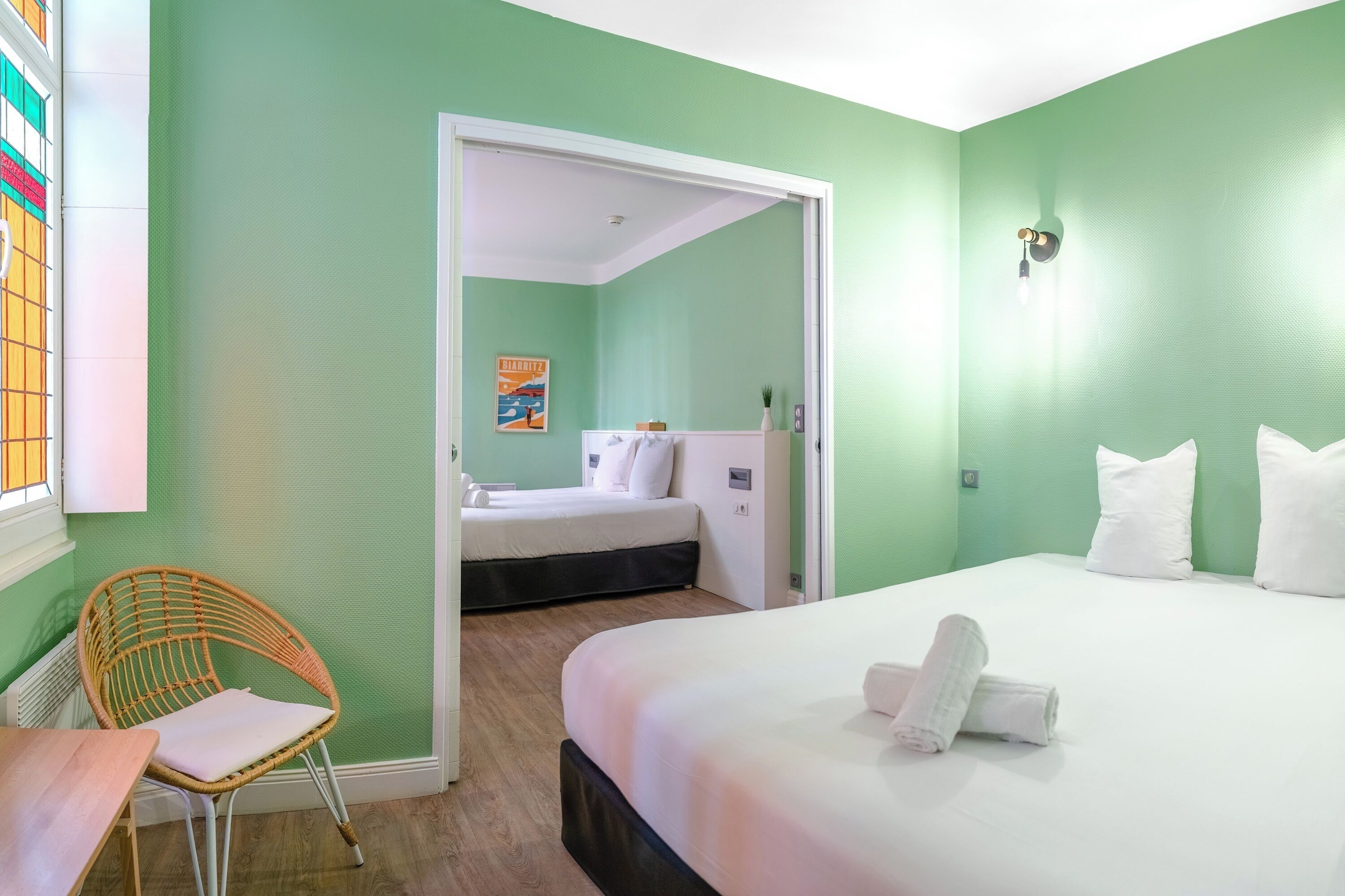 Une chambre d’hôtel avec un lit, une chaise, une petite table et une porte donnant sur une autre pièce.