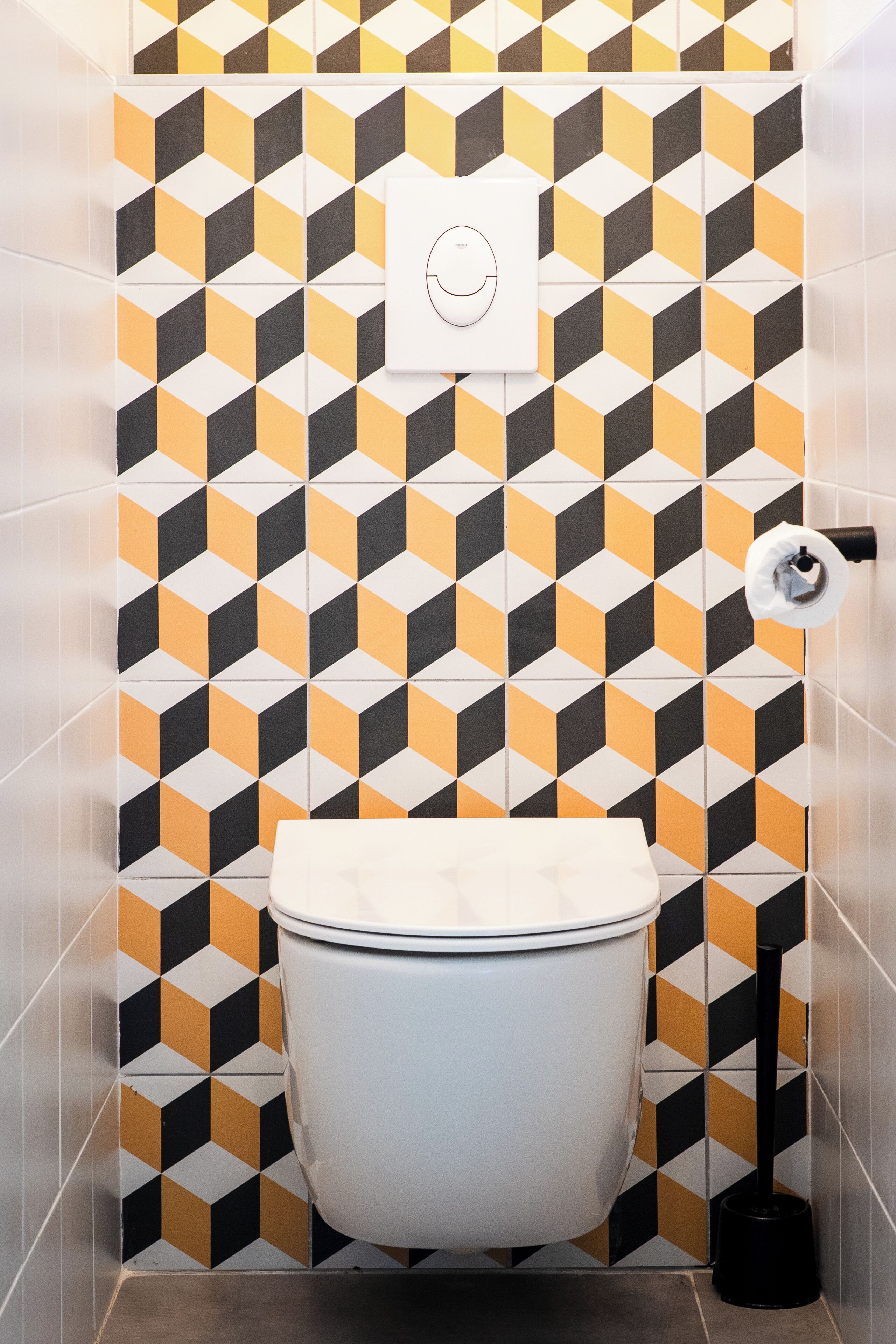 Et badeværelse med toilet, toiletpapirholder og en snave.