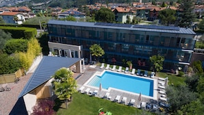 A modern hotel with a swimming pool, surrounded by lush greenery and mountains. - Park Hotel Il Vigneto (Arco)
