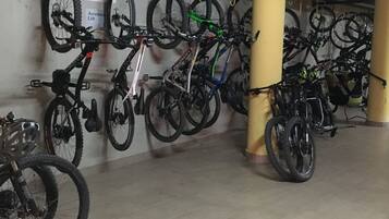 Ett område för cykelförvaring med flera cyklar hängande på krokar och några få stående på golvet.