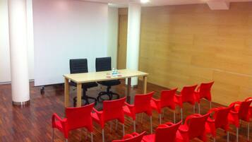 Une salle de conférence avec une longue table et de nombreuses chaises rouges.