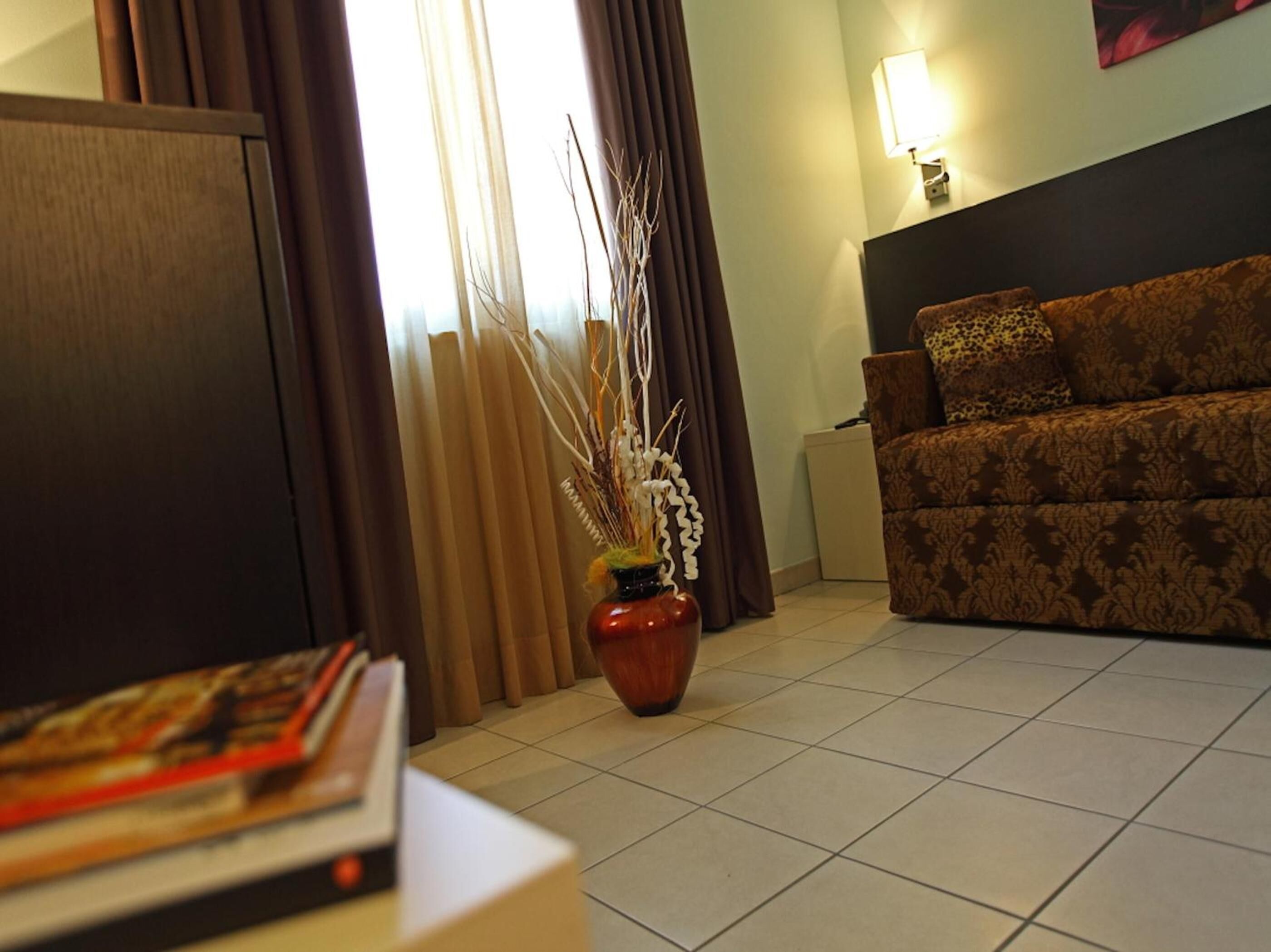 A living room with a sofa, a vase with branches, and a lamp.