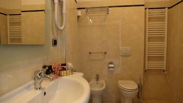 A bathroom with a sink, bidet, toilet, towel rack, and a mirror.