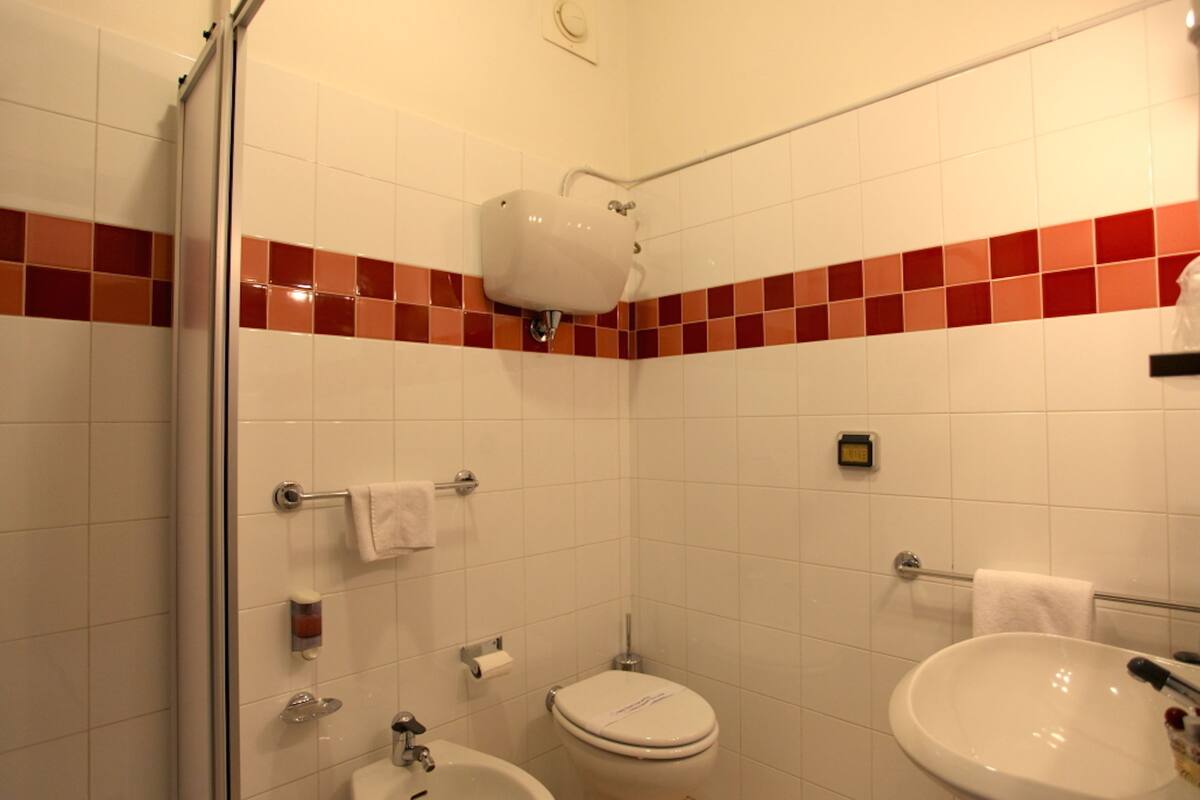 A bathroom with a toilet, bidet, sink, and a shower area.