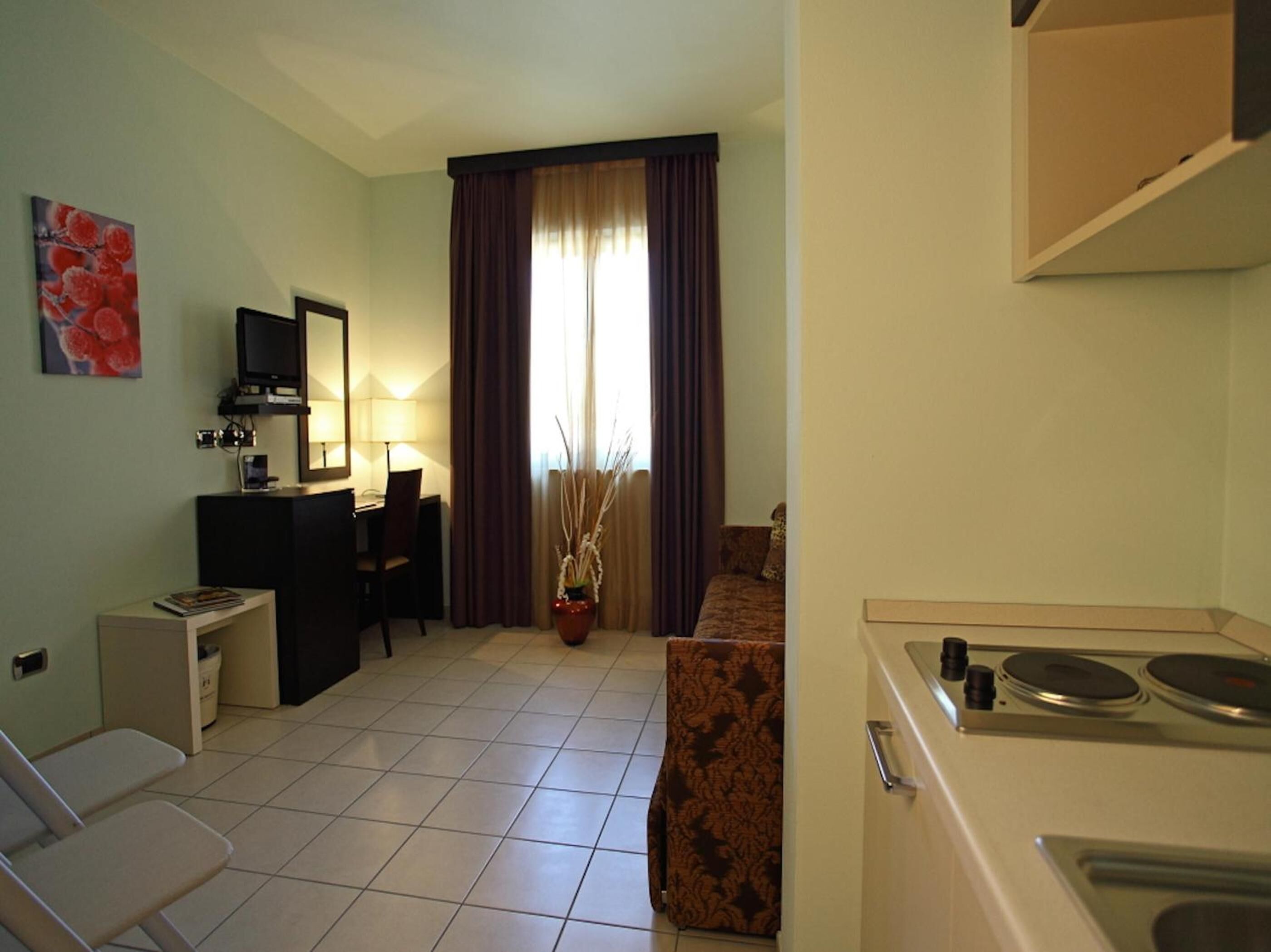 A compact hotel room with a kitchenette, a dining area, and a living space.