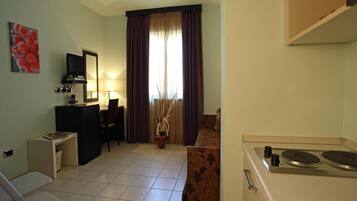 A compact hotel room with a kitchenette, a dining area, and a living space.