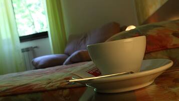 Eine Tasse auf einem Untertasse auf einem Tisch in einem Zimmer mit Fenster, Sofa und Heizkörper.