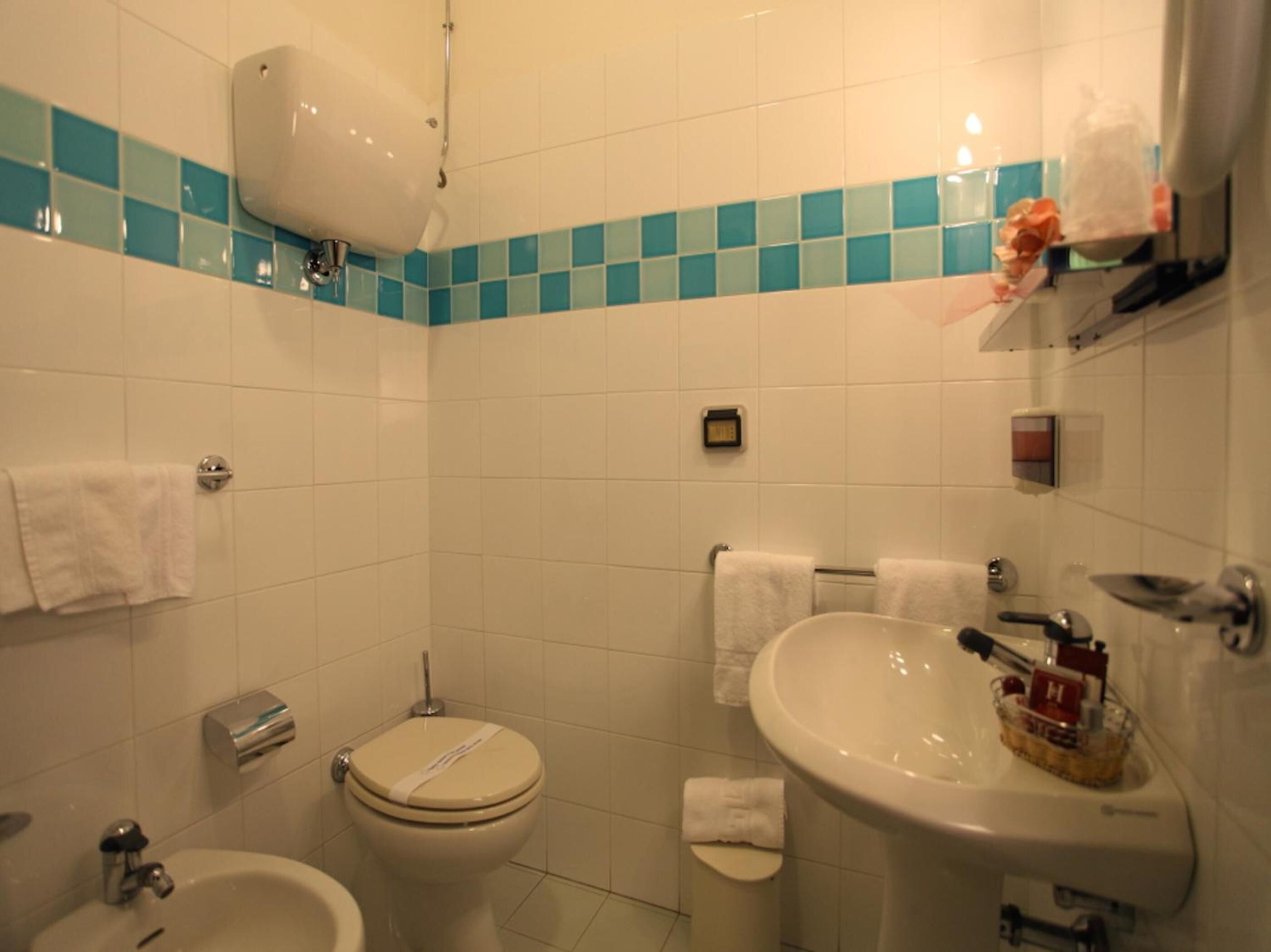 Un bagno con WC, bidet, lavandino e porta asciugamani.