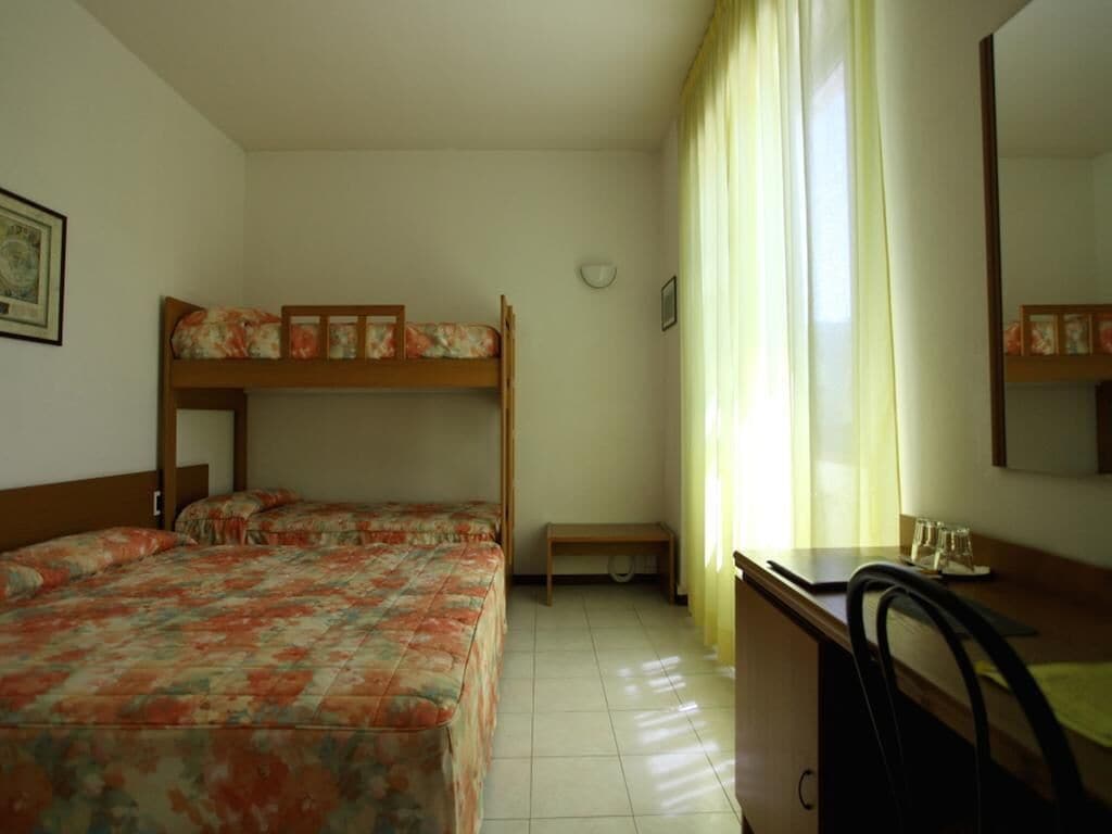 Une chambre avec deux lits superposés, un bureau, une chaise et une fenêtre avec des rideaux.