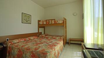 A room with two beds, one with a bunk, a desk, a chair, and a window with curtains.