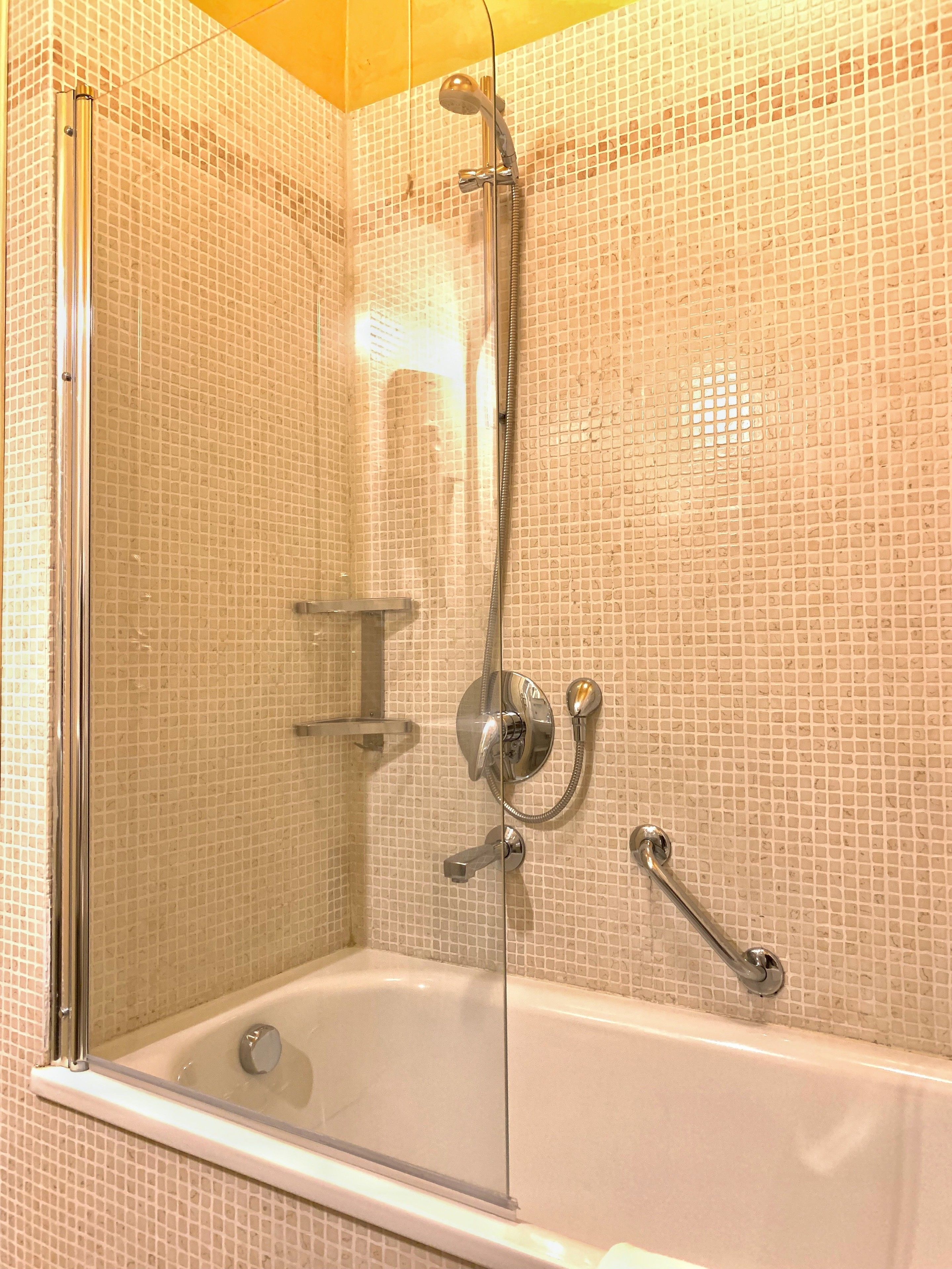 A bathroom with a glass-enclosed shower, a bathtub, and tiled walls.