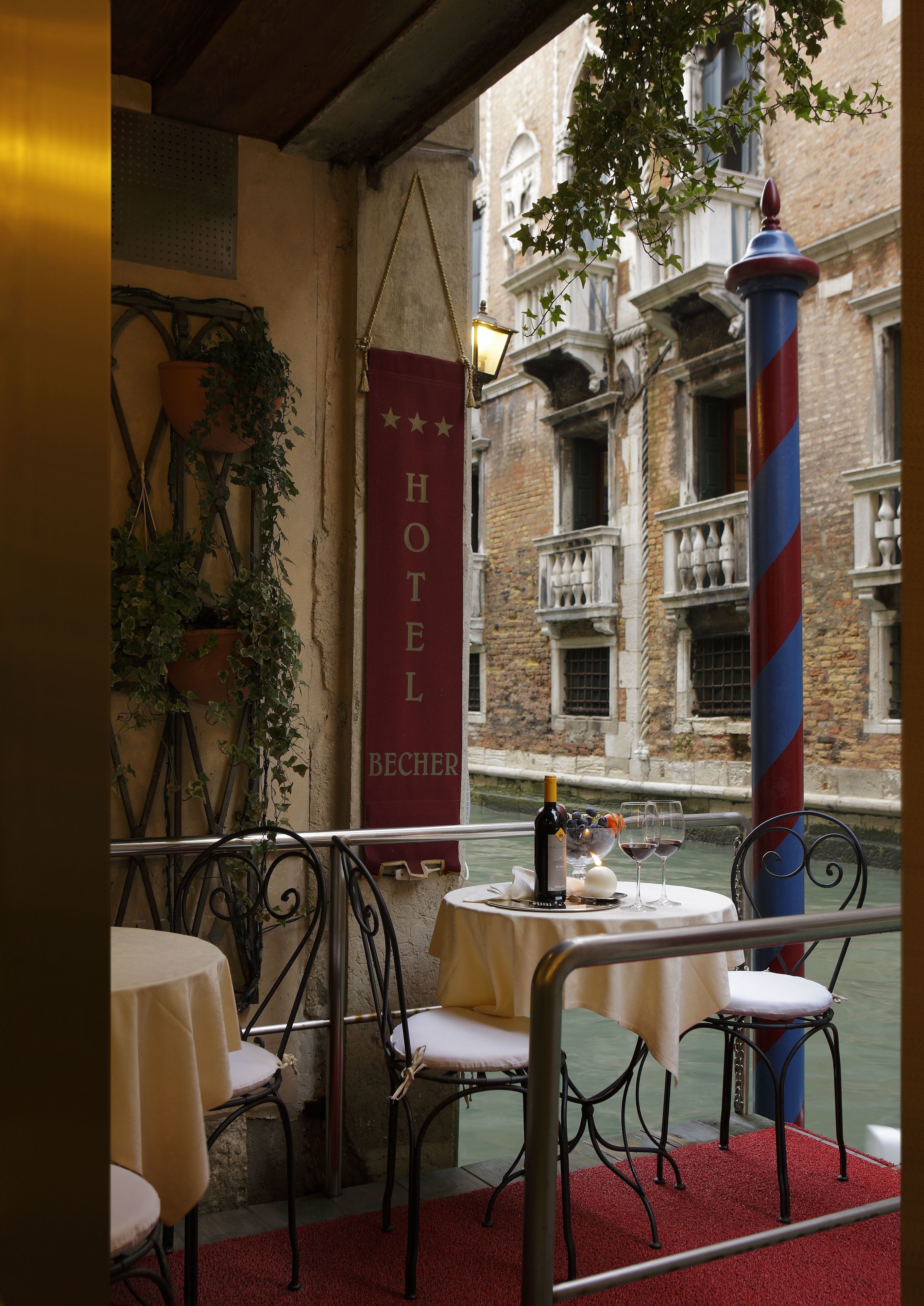 A hotel terrace with tables and chairs, a flag, and a view of historic buildings.