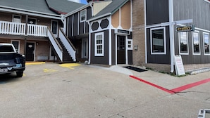 A building with a staircase leading to a second floor, a sign indicating an office, and a parking area with a yellow line. - Stratford House Inn Branson (Branson)