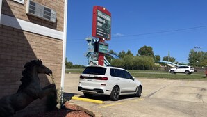 A parking lot with a white SUV, a horse statue, and a sign for Stratford House Inn. - Stratford House Inn Branson (Branson)