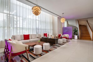 A modern living room with a sofa set, coffee table, ottomans, and a staircase.