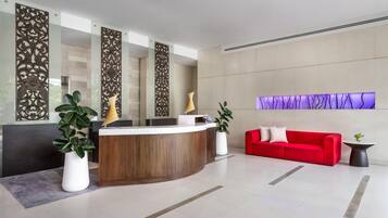 Una zona de recepción con un mostrador de madera, un sofá rojo y paneles decorativos en las paredes.