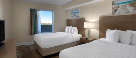 A hotel room with two beds, a TV, a desk, and a window with curtains.