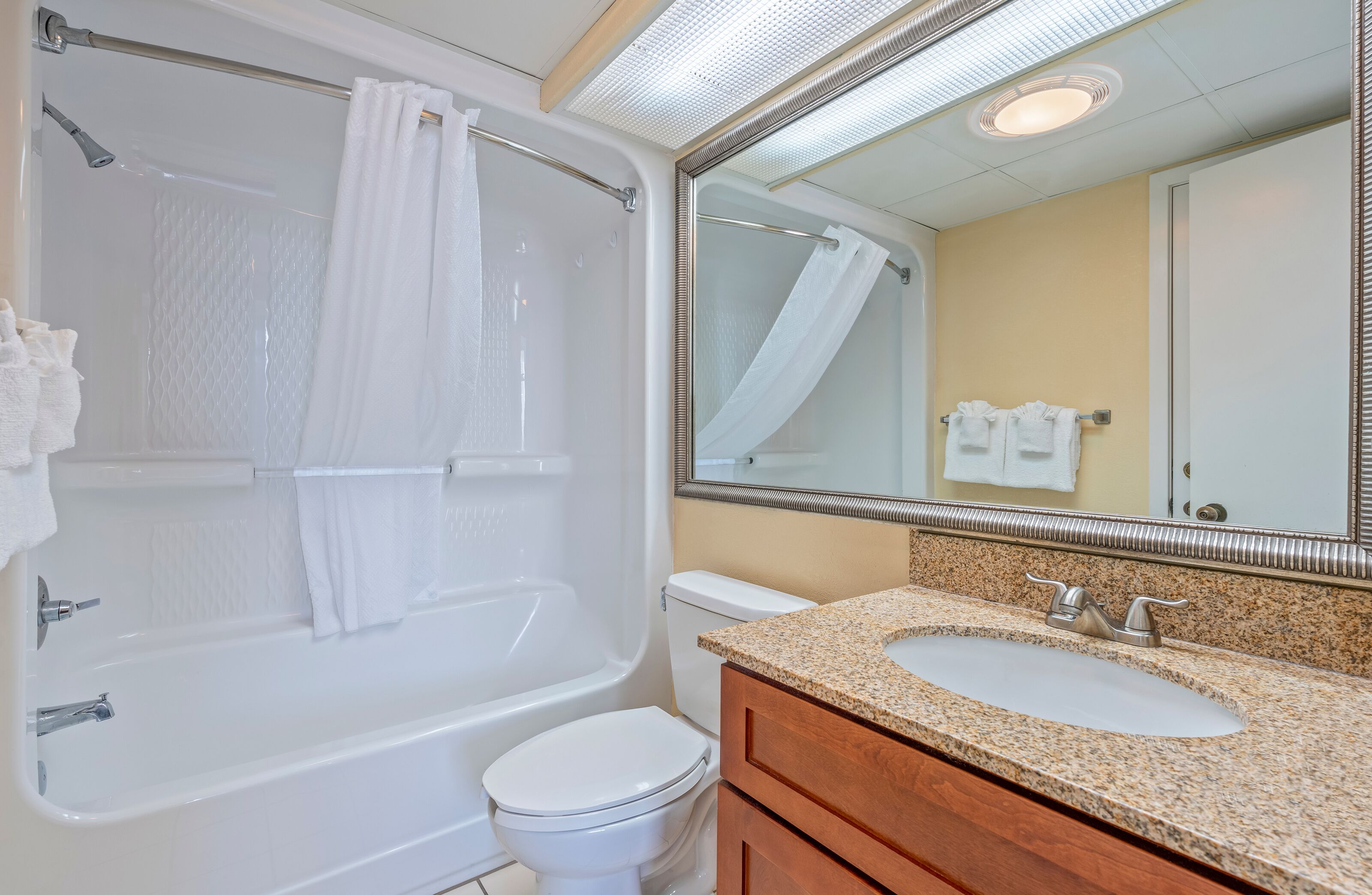 A bathroom with a bathtub, toilet, and vanity with a sink.
