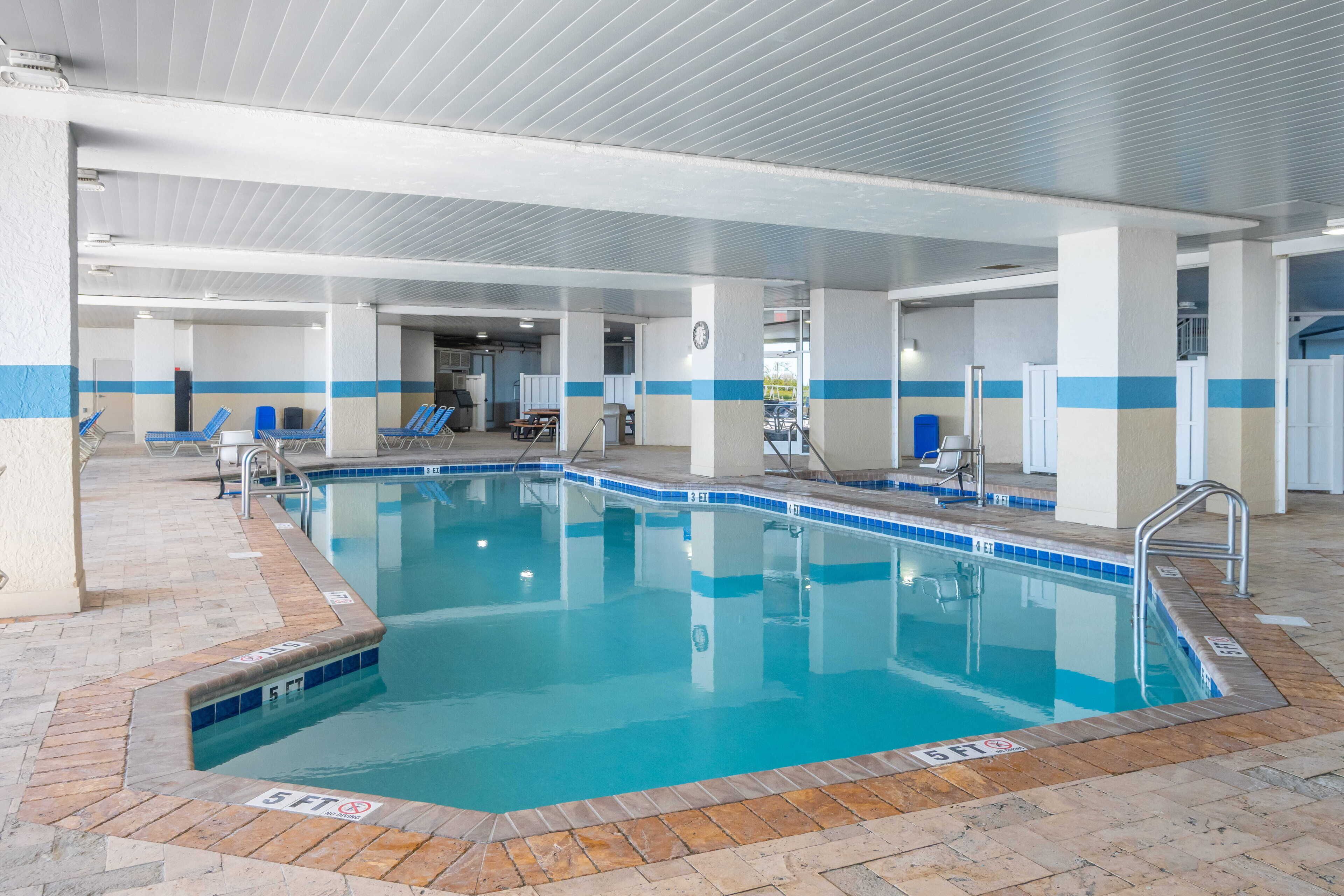 An indoor swimming pool with clear water, tiled edges, and a 5 ft depth marker.