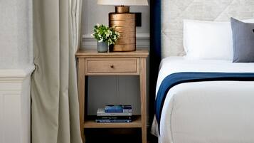 A neatly arranged hotel room with a bed, bedside table, lamp, and a mirror on the wall.