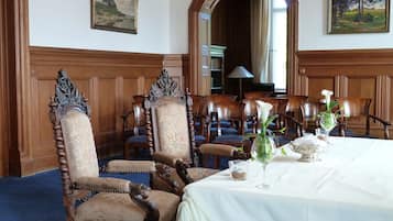 A formal dining room with ornate wooden chairs, a white tablecloth, and floral centerpieces.