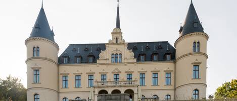 A large, historic building with two prominent towers and a central spire.