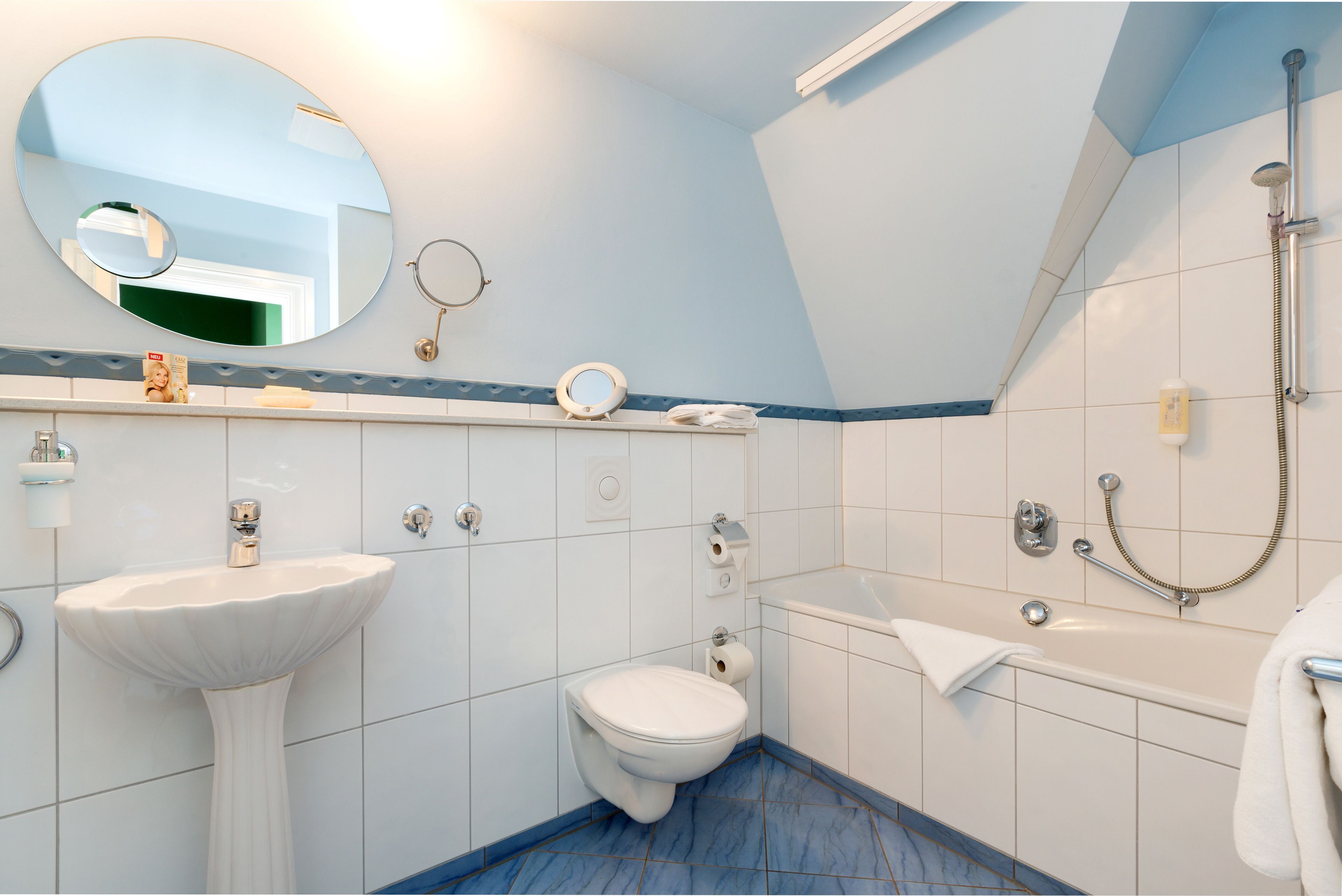 Un baño con lavamanos pedestal, inodoro, bañera y ducha con cabezal de ducha de mano.