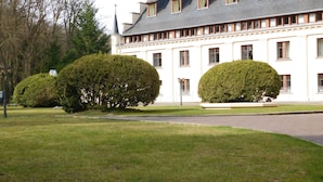 A large, white building with a symmetrical facade, multiple windows, and a prominent tower. - Schlosshotel Ralswiek (Ralswiek)