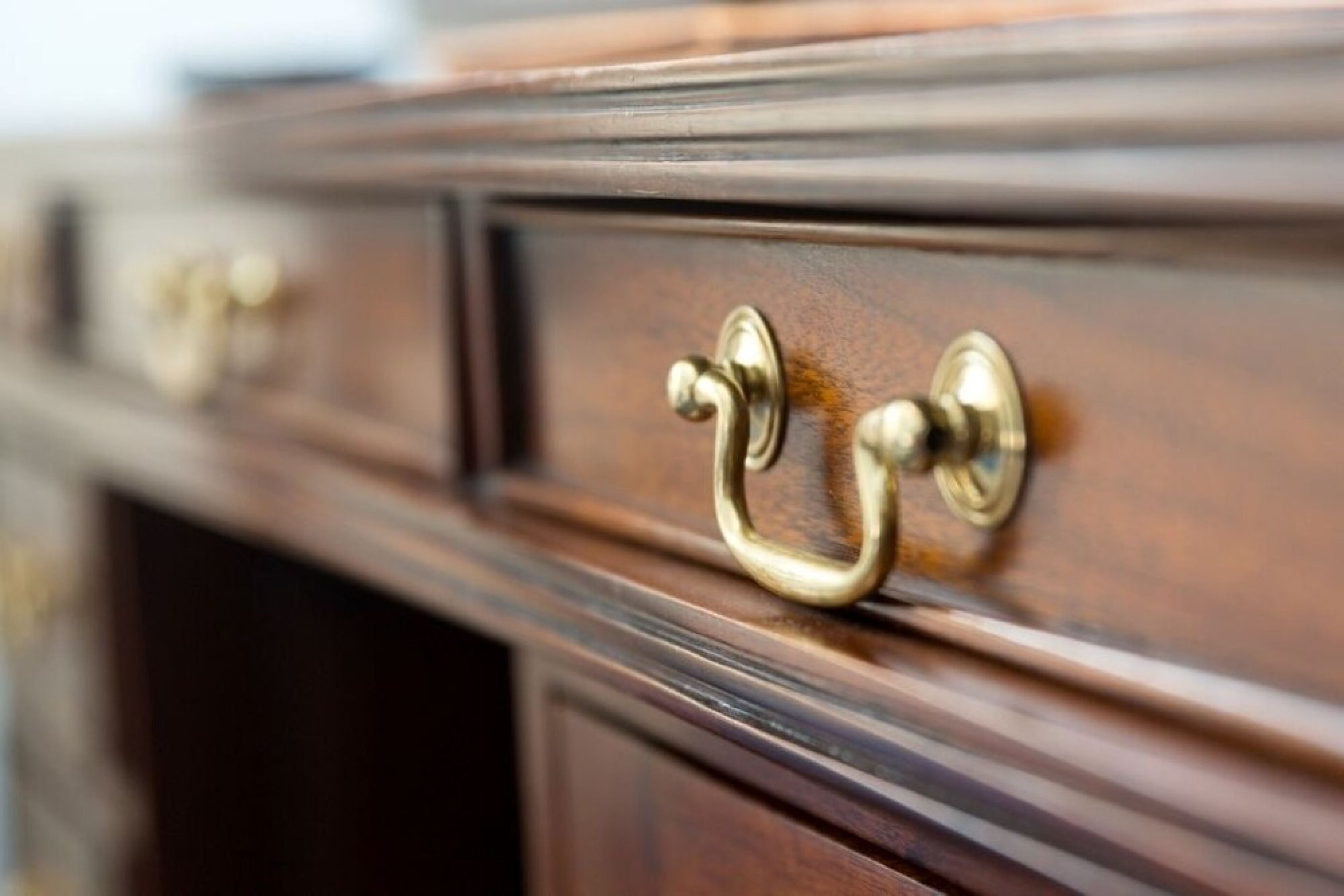 Een detail van een houten dressoir met messing handgrepen.