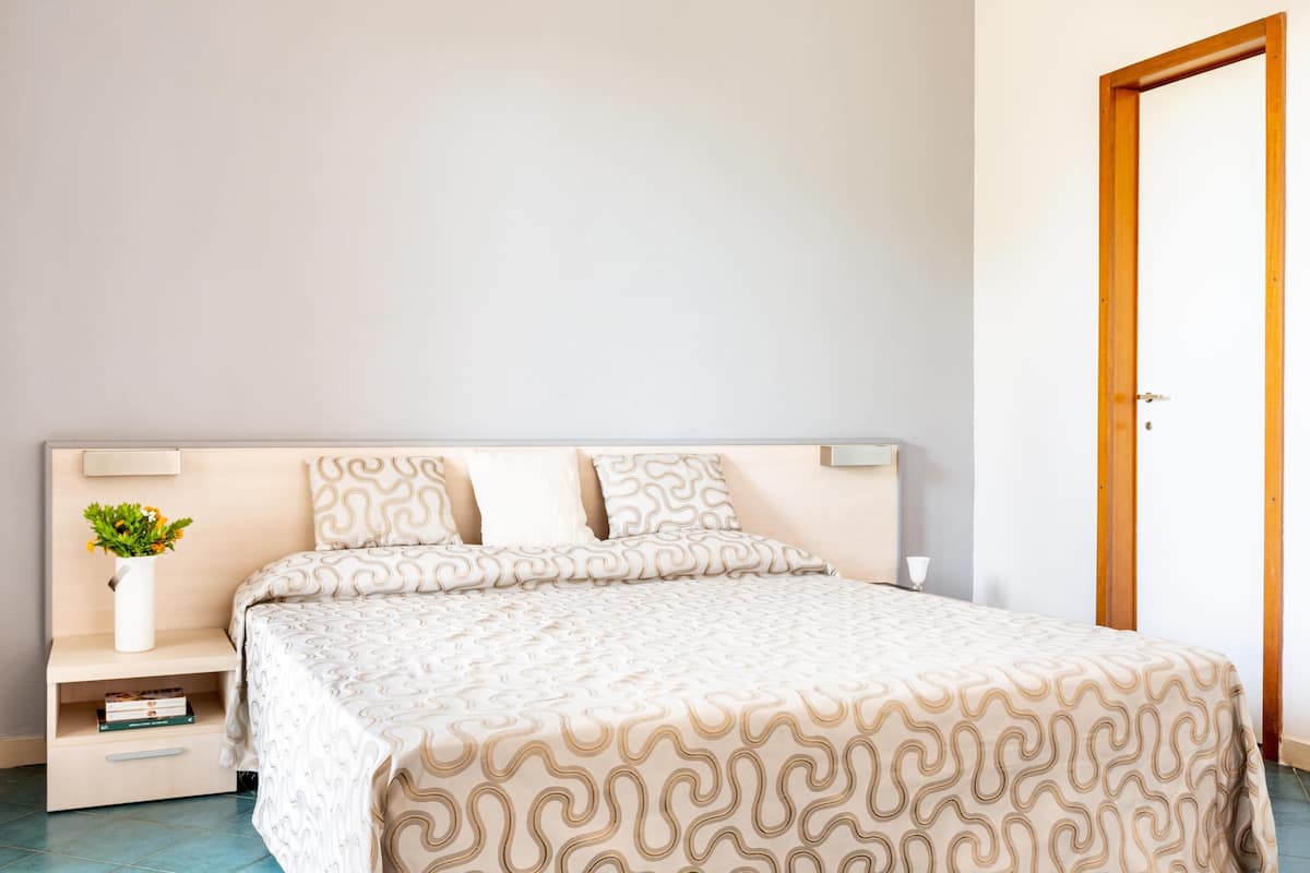 Un dormitorio con cama, mesitas de noche y una puerta.