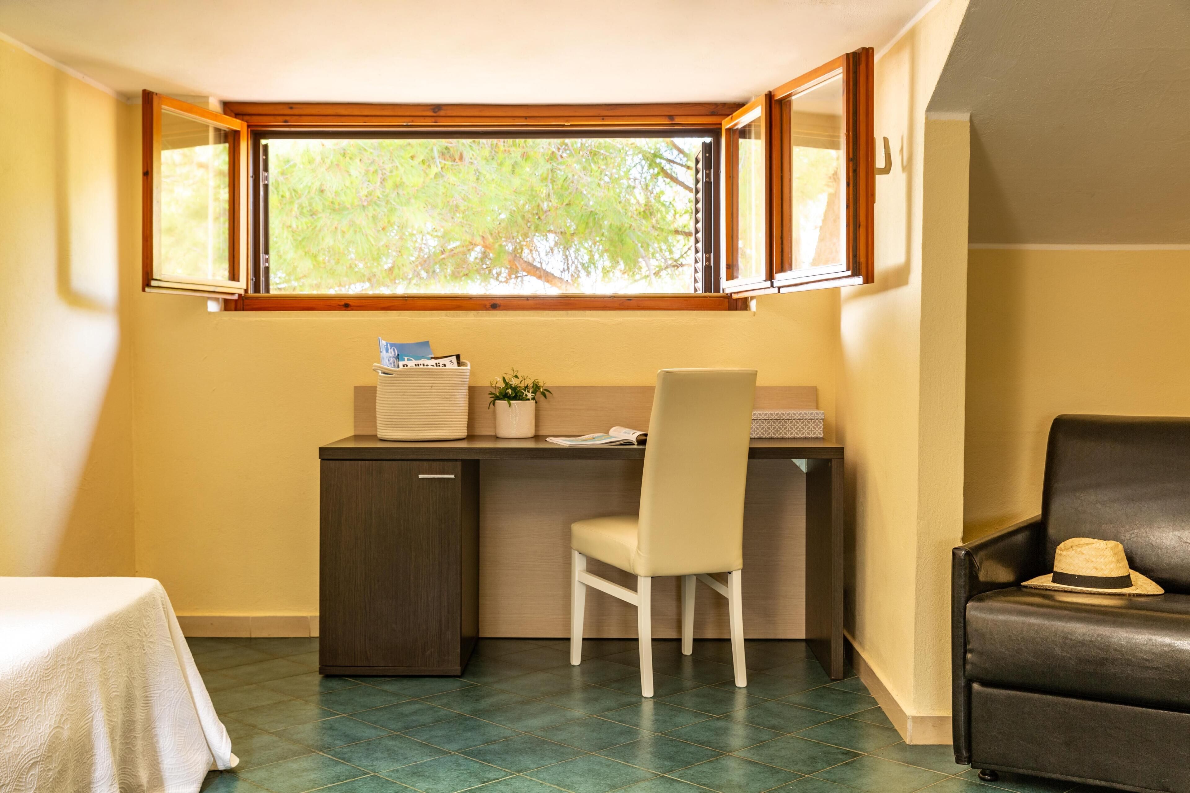 Una habitación pequeña con escritorio, silla y un sofá.