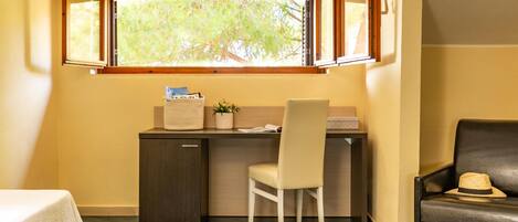 Una habitación pequeña con escritorio, silla y un sofá.
