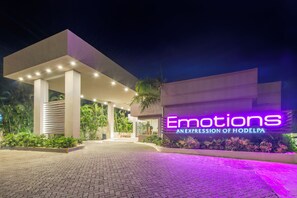 A modern hotel entrance with a neon sign reading "Emotions AN EXPRESSION OF HODELPA" and a paved walkway leading to the entrance. - Emotions by Hodelpa Puerto Plata (Puerto Plata)
