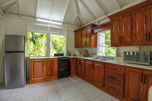 A kitchen with wooden cabinets, a stainless steel refrigerator, a stove, and a microwave.
